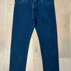 Blå jeans från Jacob Cohen - Snygga blå jeans från Jacob Cohen med klassisk femficksdesign och tydliga sömmar. Jeansen har en rak passform och är tillverkade i mjukt denimtyg. Märkets logga finns broderad på fickan och en patch baktill i mörkblått. Perfekt för dig som gillar stilrena jeans.