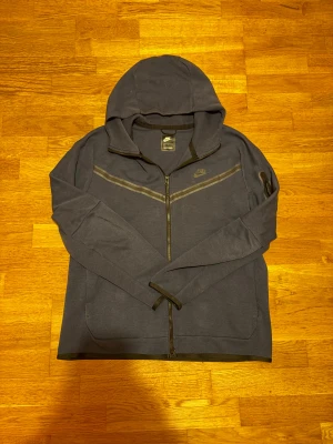 Nike Tech fleece - Mörkblå nike tech fleece i storlek L. Mycket bra skick.  68cm längd och 57cm bredd. Väldigt Snygg och bekväm tröja🙌 Skickas inom 24 timmar 🚀  Kontakta för frågor📲