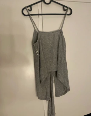 Grå omlott linnetopp Gina Tricot - Säljer en grå omlott linnetopp från Gina Tricot i storlek L. Toppen har smala axelband, knyt framtill och en snygg croppad passform. Mjuk och stretchig bomullskänsla, perfekt för sommarens chill dagar. Styla med jeans eller kjol för en laidback vibe.