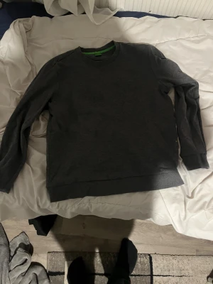 Mörkgrå sweatshirt från Esprit - Mörkgrå sweatshirt från Esprit med diskret logotyp på bröstet. Tröjan har rund hals, långa ärmar och ribbade muddar vid ärmslut och nederkant. Materialet är mjuk bomull och passformen är normal, perfekt för chill dagar.