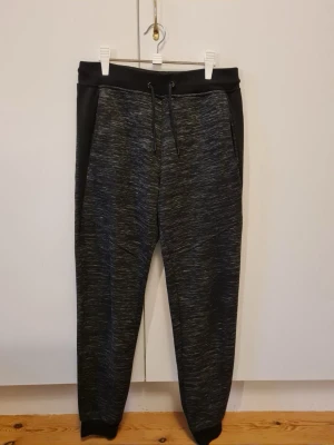 Svarta mjukisbyxor med snörning herr strl M - Byxorna är tillverkade i en blandning av polyester och bomull. Storlek M.