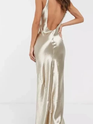 Guldig långklänning i satin - Supersnygg långklänning i glansig guldig satin med öppen rygg och smala axelband. Klänningen har en figurnära passform och faller snyggt längs kroppen. Perfekt för dig som vill sticka ut på festen eller balen!