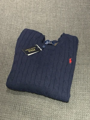 Marinblå stickad tröja Polo Ralph Lauren - Helt ny Marinblå stickad tröja Polo Ralph Lauren. Tröjan är helt oanvänd och har fortfarande prislappen kvar. Tröjan är storleken L men passar mer som M. Tröjan är gjord i 100% bomull. Hör gärna av dig vid fler frågor😊