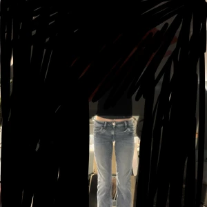 Blå bootcut jeans med låg midja - Säljer ett par blå jeans med snygg tvätt och klassisk femficksdesign. Modellen har låg midja och bootcut-ben som ger en schysst siluett. Jeansen är tillverkade i jeansmaterial och har en knappstängning framtill. Perfekta för dig som gillar en avslappnad och trendig look. Lite vridna i benen och pris går att diskuteras.