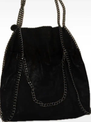 Svart axelväska från Stella McCartney - Cool svart axelväska från Stella McCartney med kedjedetaljer runt kanterna och som axelrem. Väskan är tillverkad i syntetmaterial med mockakänsla och har en rund metallbricka med logga. Inuti finns flera fack och en liten matchande necessär med dragkedja. Längd: 40cm och bredd: 36cm. Ordinarie pris 12000kr Vid frågor skriv privat till mig och skickar alltid post bevis💕