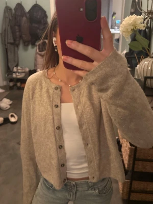 Beige kofta från Primark Cares - Säljer en beige kofta från Primark Cares i storlek S. Koftan har rund hals, långa ärmar och knappar framtill. Materialet är mjukt och stickat, perfekt att slänga över en topp eller t-shirt. Enkel och clean stil som funkar till jeans eller kjol.