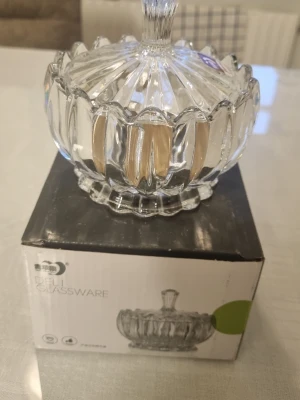 Genomskinlig glasväst med lock - Säljer genomskinlig glasväst från Deli Glassware. Västen har ett lock med handtag och ett snyggt räfflat mönster runt om. Perfekt för dig som gillar klassisk design och vill ha något som sticker ut på hyllan.