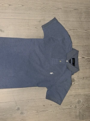 Ljus Blå Polo Ralph Lauren piké S - Snygg blå pikétröja från Polo Ralph Lauren i custom fit. Klassisk krage, två knappar och ikonisk broderad logga på bröstet. Materialet är mjuk bomull som känns skönt mot huden. Perfekt för dig som gillar stilrena och tidlösa plagg.