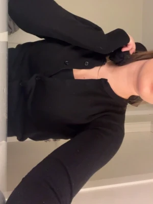 Svart croppad kofta med knappar - Säljer en svart croppad kofta med lång ärm och rundad hals. Koftan har knappar hela vägen framtill och är tillverkad i ett mjukt stickat material. Perfekt att styla med jeans eller kjol för en chill look.