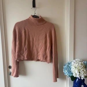 Rosa ribbad polotröja från BikBok - Superfin croppad polotröja från BikBok i en mjuk, ljusrosa nyans. Tröjan är ribbstickad med lång ärm och hög krage, perfekt för lager på lager. Snygg till både jeans och kjol för en chill look.