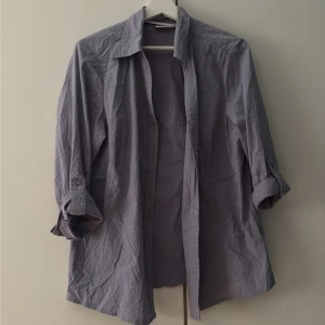 Ljuslila skjorta från Lindex, strl 44 - Ljuslila skjorta från Generous by Lindex i storlek 44. Skjortan har klassisk krage, knappar framtill och långa ärmar som kan vikas upp och fästas med knapp. Tillverkad i mjuk bomull, perfekt för en avslappnad och stilren look.