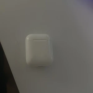 AirPods 2 - Säljer ett par Apple AirPods 2 med laddningsetui. Fungerar utmärkt och är i fint skick utan synliga repor eller skador. Perfekt för trådlös musik och samtal. Laddningsindikatorn lyser grönt, vilket visar att de fungerar.