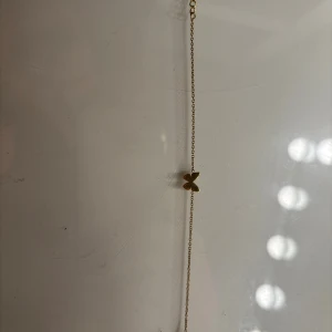 Edblad armband guld, med fjäril - Snyggt och tunt armband i guldton med en liten fjärilsberlock i mitten. Kedjan är finlänkad och ger ett stilrent intryck, perfekt för dig som gillar minimalistiska smycken med en söt detalj.