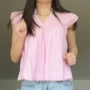 Ljusrosa blus med volangärm - Söt ljusrosa blus med v-ringning och volangärmar. Blusen har en luftig passform och är tillverkad i ett lätt, skrynkligt bomullstyg som ger en avslappnad känsla. Perfekt för vår och sommar.