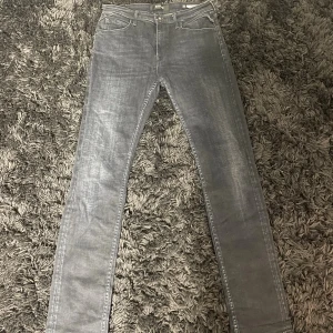 Replay Jacksy grå jeans, stl 29 - Säljer ett par grå Replay Jacksy jeans i klassisk femficksmodell. Jeansen har smal passform, raka ben och snygga slitningar för en cool look. Tillverkade i mjukt jeansmaterial med stretch för extra komfort. Perfekta för dig som gillar stilrena och moderna jeans.💯