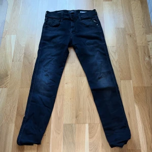 Replay Anbass Hyperflex svarta jeans - Säljer ett par svarta Replay Anbass Hyperflex jeans med klassisk femficksdesign och snygga detaljer på fickorna. Jeansen har smal passform och stretchigt material som ger extra komfort. Perfekta för dig som gillar stilrena och moderna jeans. Jeansen har inte inte används nånting för att dom har inte passat.