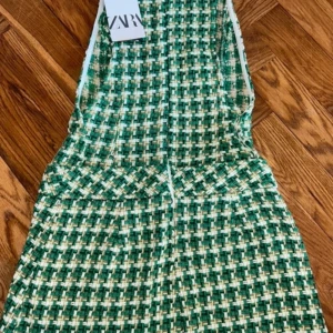 Grön rutig klänning från Zara - Superfin kort klänning från Zara i grönt och vitt rutigt mönster. Klänningen är ärmlös. Materialet känns lite tjockare och strukturerat, perfekt för en trendig look. Snygg passform och cool retrovibe.