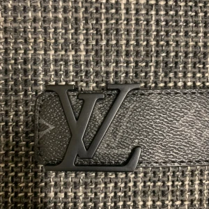 Svart Louis Vuitton skärp i skinn - Snyggt svart Louis Vuitton bälte i skinn med klassiskt LV-monogram och mattsvart LV-spänne. Bältet har diskret mönster och tydlig Louis Vuitton-logga på spännet. Perfekt accessoar för att lyfta din outfit.