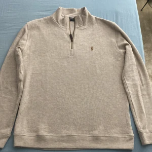 Beige half zip tröja från Polo Ralph Lauren - Snygg beige långärmad tröja från Polo Ralph Lauren med klassisk broderad logga på bröstet. !(Är stor i storlek)! !(Står storlek S men är M)!. Tröjan har half zip-dragkedja och är tillverkad i mjuk bomull. Perfekt kvalité.