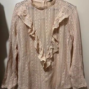 Blus strl M  - Virkad beige blus med volanger i strl M från Kappahl.  Knappar baktill.  Mycket fint skick. Material: bomull och nylon 