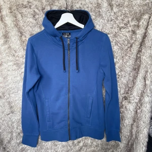 Blå hoodie från Clique med dragkedja - Säljer en blå hoodie från Clique i storlek M/38. 