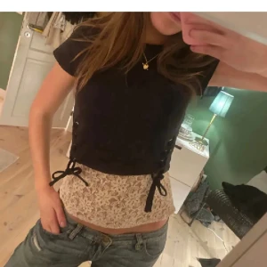 Svart croppad topp med snörning - Säljer en svart croppad topp med snörning i sidorna och korta ärmar. 