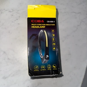 CB-689-1 Multi-Function Induction Headlamp - COBA CB-689-1 pannlampa med rörelsesensor, 1200mAh inbyggt batteri, USB-C laddning och bred COB LED-belysning. Perfekt för cykling, fiske, camping och äventyr. Lätt vikt och vattenskyddad. Kartongen har mindre skador men produkten är ny.