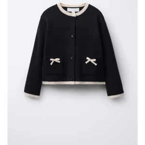 Svart kofta med rosetter - Supersöt kofta med beige detaljer och två fickor framtill, dekorerade med små rosetter. Perfekt för dig som gillar en söt och stilren look. Använd några få gånger💖💖☺️