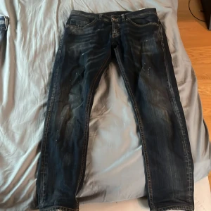 Mörkblå skinny jeans från Dondup - Snygga mörkblå skinny jeans från Dondup med slitningar och coola detaljer. Klassisk femficksmodell med kontrastsömmar och diskret tvättad look. Märke på bakfickan och läderpatch i midjan. Perfekta för dig som gillar en smal passform och italiensk design.