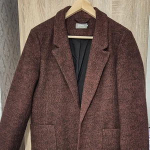 Kappa - ONLY  - Elegant kappa från Only i en vacker vinröd färg. Den har en klassisk krage, knäppning fram och praktiska fickor. Perfekt för att hålla värmen med stil.  Användes 1 gång. Det är som ny.  Storlek: L Pris: 230