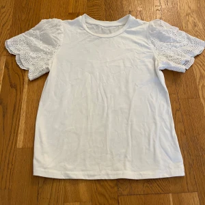 Vit topp med broderade volangärmar - En T-shirt men spets på axlarna, nästan inte använt 