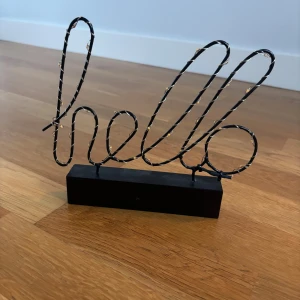 LED-bordslampa 'hello' dekor - Dekorativ LED-lampa i form av ordet 'hello', svart metalltråd med små LED-lampor. Drivs av 2 AAA-batterier (ingår ej). Perfekt som belysning eller dekoration. Locket till batterierna är borta.