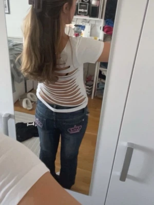 Vit t-shirt med öppen rygg och slitsar - Säljer en vit t-shirt med korta ärmar och coola slitsar i ryggen som ger en edgy vibe. Materialet är mjukt och känns som bomull. Perfekt för dig som vill sticka ut med en unik detalj på ryggen. Passformen är normal och t-shirten är enkel att matcha med jeans eller shorts.