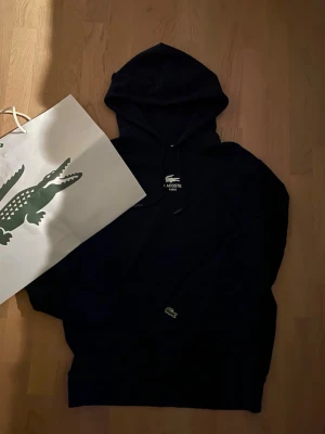 Lacoste hoodie - Ikonisk lacoste hoodie från Frankrike när jag gjorde roadtrip ditt. Köpte hoodien eftersom den satt perfekt på mig och hade skön loga på ryggen. Nu har jag växt ut den och säljer den. Hoodien har inga defekter, pris är ej huggit i sten, flytt på med prisförlsag!🙌👀