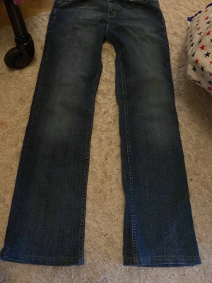 Blå jeans från Esprit med broderad ficka - Snygga blå jeans från Esprit med klassisk rak passform och coolt gult broderi på bakfickan. Jeansen har normal midja, bälteshällor och knäppning fram. Materialet är slitstarkt denim i bomull och de har en stilren look som funkar till många outfits.