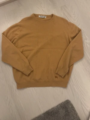 Beige stickad tröja från Burberrys - Säljer en beige stickad tröja från Burberrys i 100% geelong lammull, tillverkad i Skottland. Passar storlek M. Bra kondition