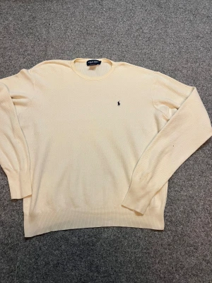 Beige bomullströja Polo Golf XL - Äkta. Snygg beige långärmad tröja från Polo Golf Ralph Lauren i 100% bomull. Klassisk rund hals och diskret broderad logga på bröstet. Perfekt för dig som gillar stilrena och tidlösa plagg. Passar dig som vill ha en normal passform.