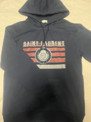 Saint laurent hoodie M - En hoodie från saint lauren i storlek M, passar runt 180 cm bra, bra skick och den är köpt på plick så håll det i åtanke, skriv vid någon fundering.