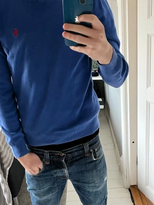 Blå tröja från Polo Ralph Lauren S - Säljer en blå långärmad tröja från Polo Ralph Lauren i slim fit. Tröjan är gjord av mjuk pima bomull och har det klassiska röda Polo-logot broderat på bröstet. Rund hals och ribbade muddar vid ärmslut och nederkant. Hör av er vid funderingar😁