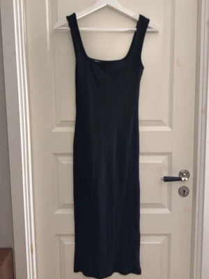 Svart ribbad långklänning - Säljer den här ribbade långklänningen med tjocka axelband. Den går ungefär 20cm ovanför fötterna på mig som är 167cm lång 