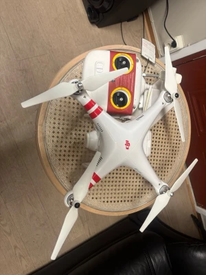 DJI Phantom 2 Vision+ (PV330) - DJI Phantom 2 Vision+ drönare med fjärrkontroll och kamera. Modellen PV330, synligt batteri och landningsställ. Viss kosmetisk slitage på landningsstället, men i övrigt gott skick. Perfekt för flygfoto och videoinspelning. Komplett med tillbehör.