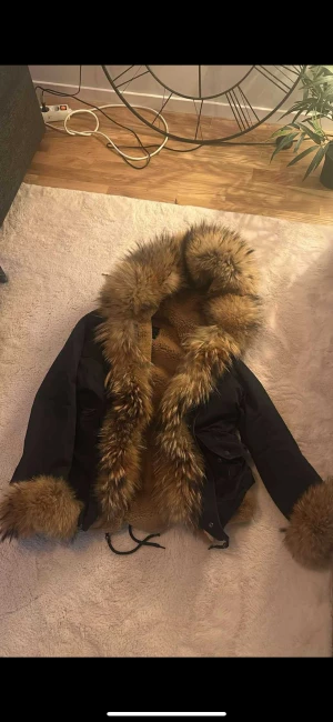 Svart pälsjacka med fluffig huva - Nypris 6000 kr, säljer för 2000 kr. Knappt använd alls
