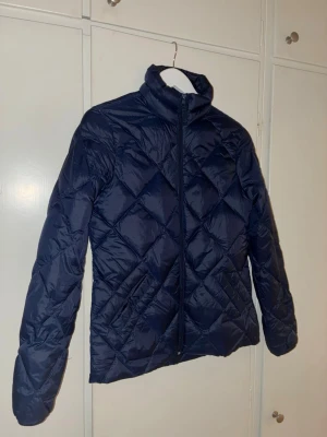 Hampton republic lättvikt jacka st S - Quiltad pufferjacka i mörkblått från Hampton republic med hög krage och dragkedja framtill. Jackan har ett snyggt rutmönster, långärmade ärmar och en patch med logga på ena armen. Perfekt för dig som vill ha en stilren och varm jacka.