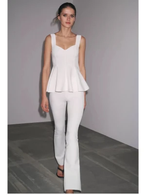 Vit peplumtop med breda axelband - Säljer en stilren vit peplumtop från Zara med breda axelband och v-ringad hals. Toppen har en figurnära passform upptill och ett utsvängt parti nedtill som ger en snygg siluett. Perfekt att styla med jeans eller kostymbyxor.