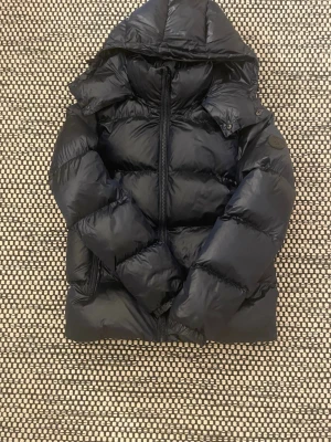 Svart glansig  pufferjacka från Everest i storlek xs. - Helt ny!! Säljer en svart pufferjacka från Everest med huva. Märke syns på ärmen och insidan. Köpte den för 1000kr så nu säljer jag den för 800kr men pris går såklart att diskutera!