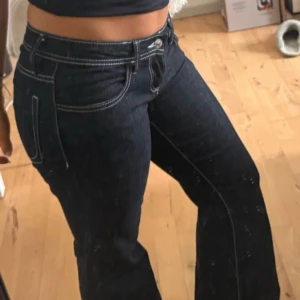 Svarta lågmidjade bootcut jeans med kontrastsömmar - Snygga svarta jeans med bootcut-modell och vita kontrastsömmar. Klassisk femficksdesign och låg midja. Jeansen har en figurnära passform upptill och utsvängda ben, vilket ger en trendig siluett. Tar gärna mått och fler bilder om det behövs! 🩵