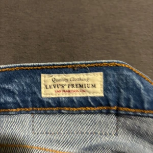 Levi's Premium 501 blå jeans - Klassiska Levi's Premium 501 jeans i mellanblå denim. Rak passform med knappgylf, fem fickor och snygga kontrastsömmar. Perfekta för dig som gillar tidlös stil och vill ha ett par jeans som funkar till allt. Ikonisk Levi's-lapp bak i midjan. Storlek: W33 L28. Pris går att diskutera 
