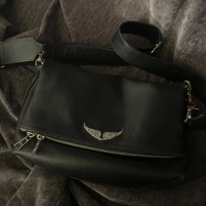 Svart axelväska Zadig & Voltaire - Säljer nu min köra zadig väska då den wj kommer till användning längre. De är den stora storleken i axelräm. Finns kedja och skinn band till väskan. Finns tecken på användning men den är i mycket fint skick.