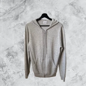 Grå hoodie i kashmir från John Henric - Mjuk och lyxig grå hoodie från John Henric i kashmir. Tröjan har huva, dragkedja framtill och två fickor. Perfekt för dig som gillar stilren och enkel design med premiumkänsla. Passar dig som vill ha något extra skönt och snyggt.