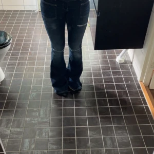 Mörkblå bootcut jeans med slitningar - Säljer ett par mörkblå jeans med bootcut-modell och snygga slitningar på låren. Jeansen har klassiska fickor fram och bak och sitter tajt upptill med utsvängda ben. Från Gina tricot 14+ st S. Använda endast en gång💕